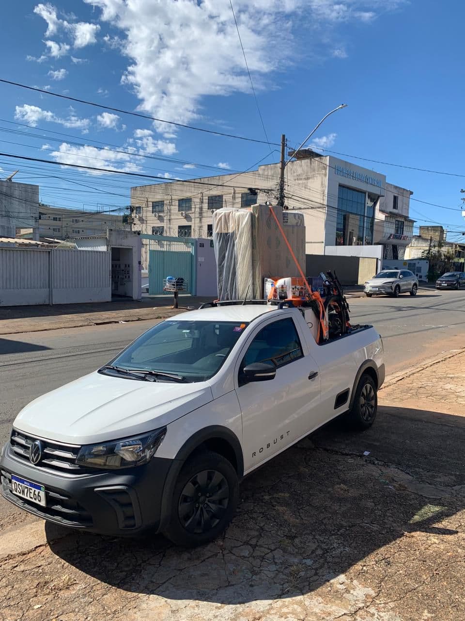 Saveiro branca carregada com colchão e itens de mudança, pronta para o frete